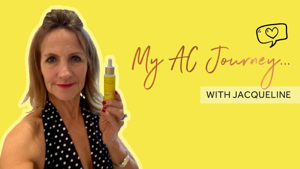 Photo on a yellow background showing a white woman with shoulder length brown hair, she is holding a bottle of Maxerum towards the camera and wearing a polka dot halterneck top