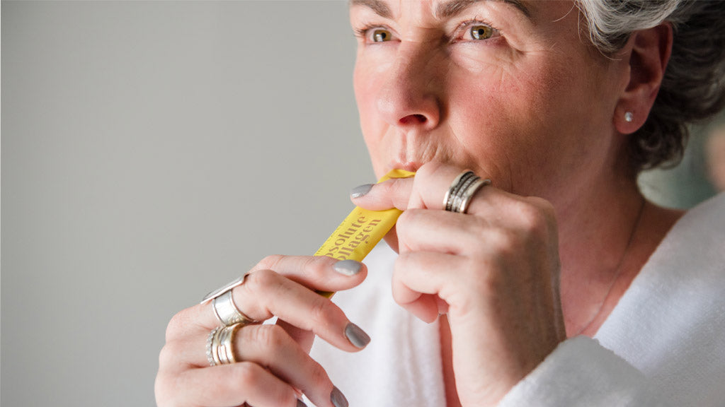 Photo showing Maxine Laceby wearing a white dressing gown and tearing open a sachet of Absolute Collagen