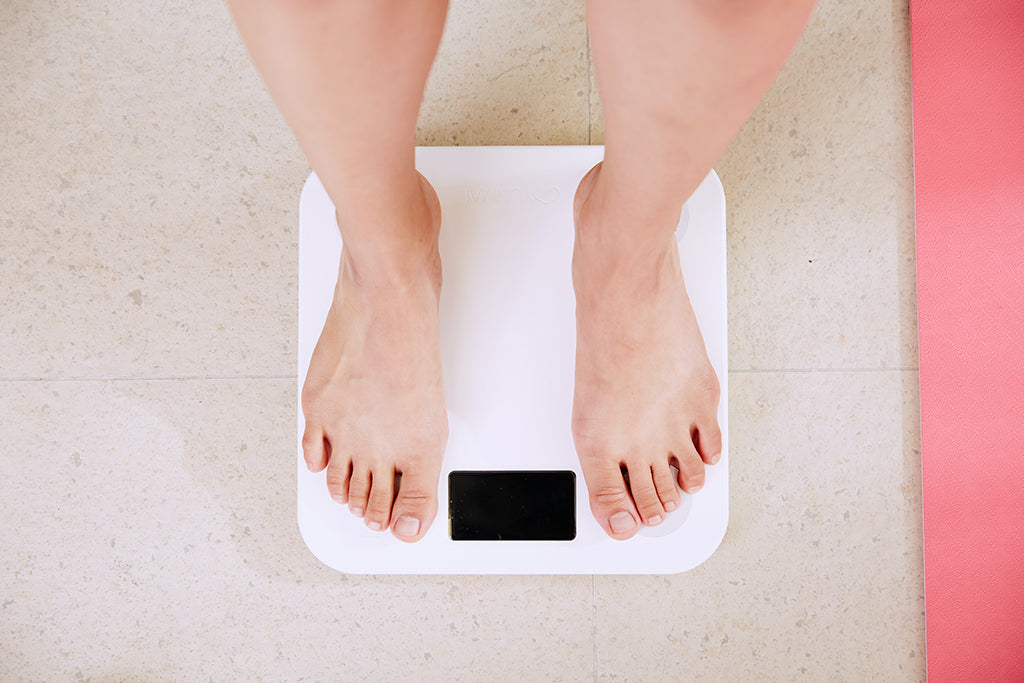 Image of a white woman's feet on bathroom scales as she weighs herself